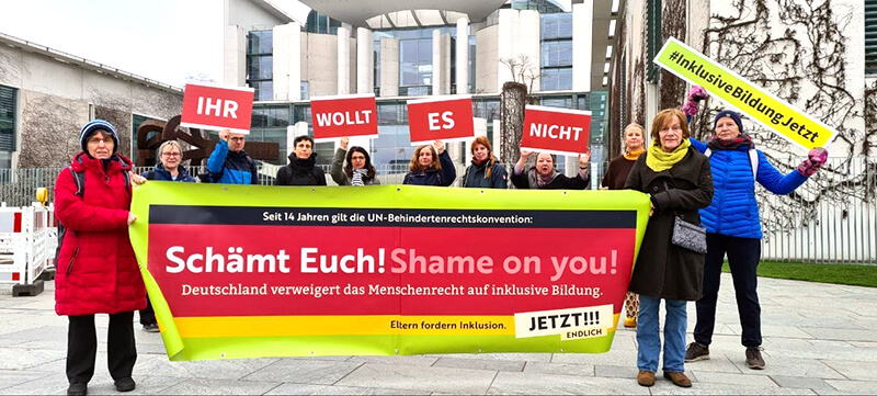 Unsere Gruppe prostestieren mit unserem Banner vor dem Bundeskanzleramt. Das Banner zeigt den Text 