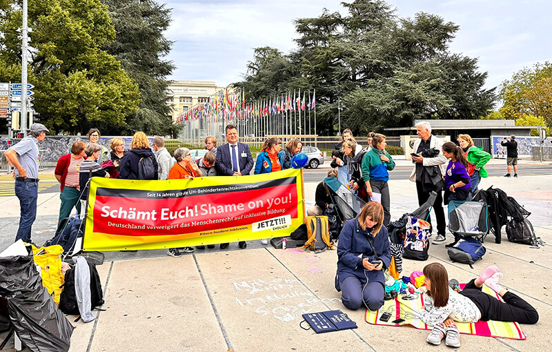 Wir prostestieren mit unserem Banner vor dem UN Gebäude in Genf. Das war zur Staatenprüfung Deutschlands im August 2023. Das Banner steht "Schämt Euch" in deutsch und englisch.